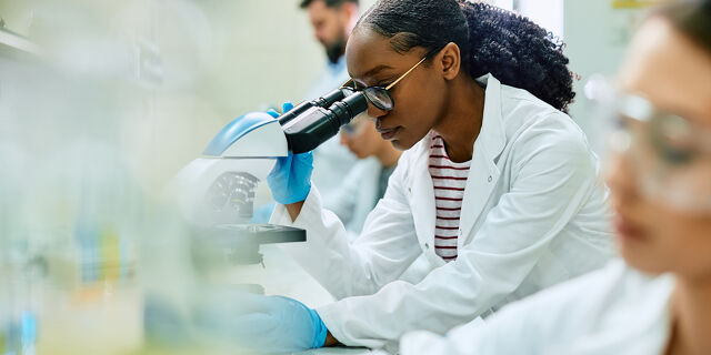 Black Female Scientist Looking Through Microscope