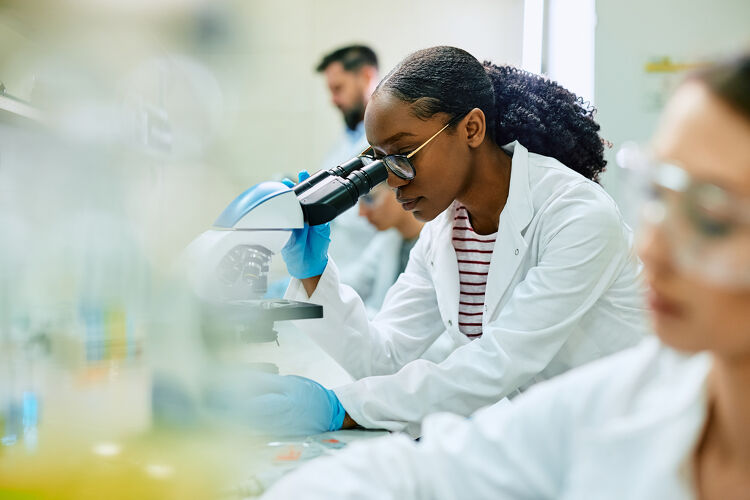 Black Female Scientist Looking Through Microscope