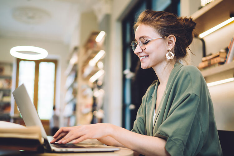 Cheerful Young Freelance Woman Typing on Laptop Cropped