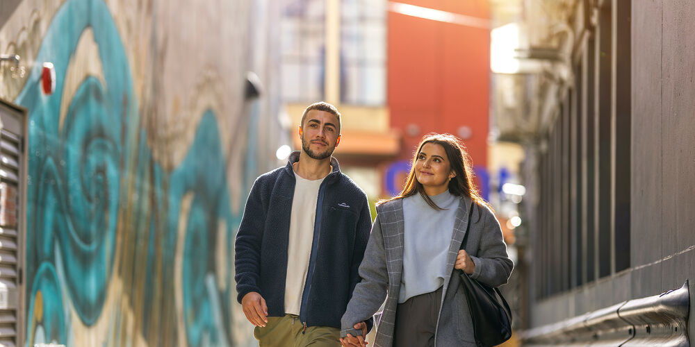 Skilled Residence Pathways Couple Walking Through a Sunlit Alley in Wellington