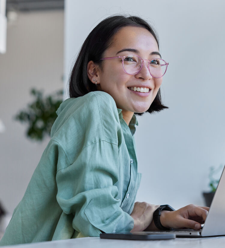 Young Lady Smiling While Working on Laptop